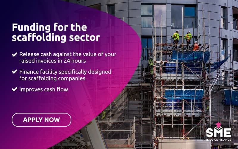 Scaffolding structure around a commercial building with construction workers working at height in a UK city.